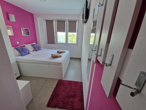 a small bathroom with a tub and pink walls at Flamingo Resort in Belgrade