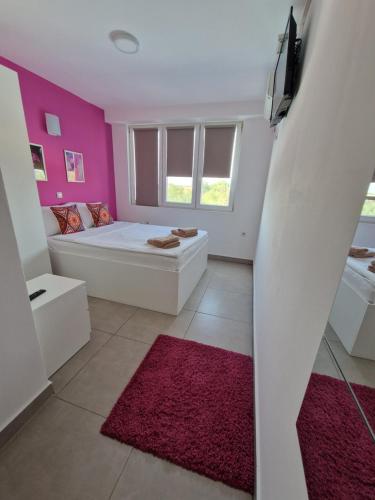uma sala de estar com um sofá branco e paredes cor-de-rosa em Flamingo Resort em Belgrado