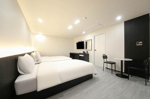 Habitación de hotel con cama blanca y mesa en Busan Seomyeon Broa Hotel, en Busan
