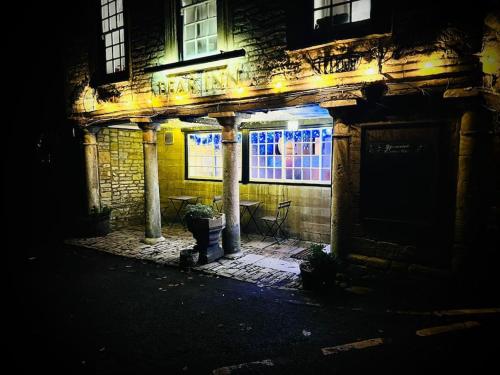 a building at night with a table and a window at BEAR INN - BISLEY in Bisley