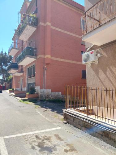 um edifício vermelho com uma cerca ao lado de uma rua em Mary T House em Campagnano di Roma