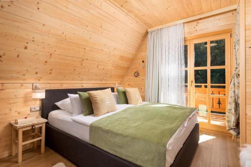a bedroom with a bed in a wooden cabin at Forest Tale - Šumska priča in Crni Lug