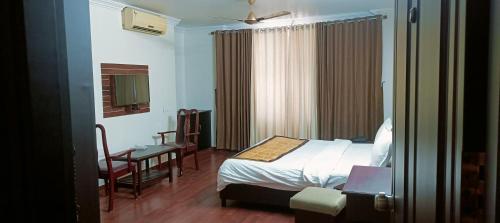 a bedroom with a bed and a table and a chair at Malanadu Tourist Home in Hosdrug