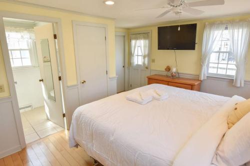 a bedroom with a white bed and a flat screen tv at Walk 3 Mins to Private Assoc Beach in Yarmouth