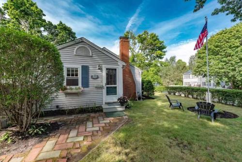 a white house with a flag in the yard at Walk 3 Mins to Private Assoc Beach in Yarmouth