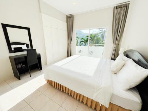a white bedroom with a bed and a desk at Prime Hill Kathu Phuket E1 in Phuket Town