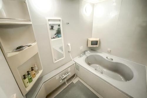 un bagno bianco con vasca e specchio di ホテル　るテラスⅡ a Sendai