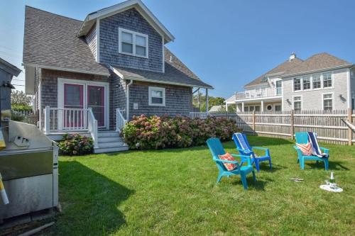 a yard with two blue chairs and a house at Walk to Beach at Historic Sears Kit Home in Dennis