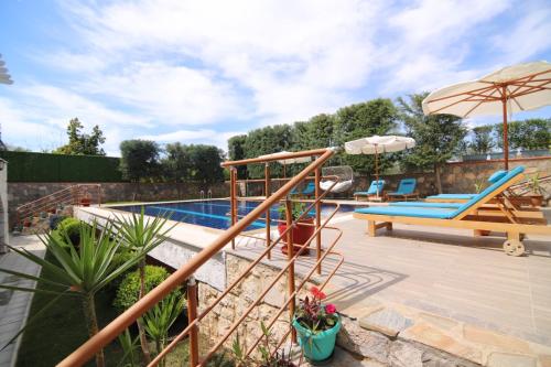 a patio with a pool with a slide and an umbrella at Villa TN - Fethiye in Fethiye