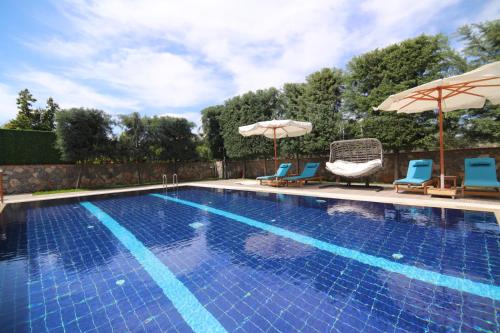 a swimming pool with two chairs and two umbrellas at Villa TN - Fethiye in Fethiye
