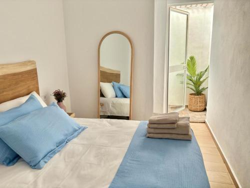 een slaapkamer met een bed met blauwe kussens en een spiegel bij El rincón de Regina in Córdoba