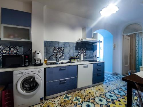 a kitchen with blue cabinets and a washing machine at Villa Angelina in Vietri sul Mare