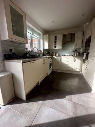 a large kitchen with white cabinets and a window at Combe Dingle, Bristol in Bristol