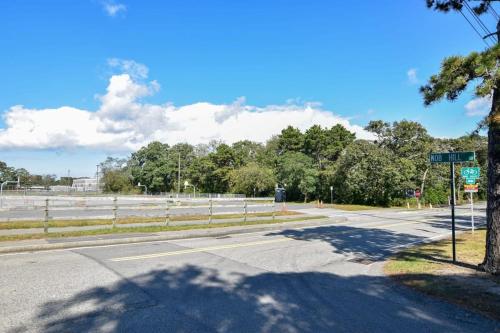 an empty road with a fence and a street sign at Quintessential Cape directly on the Cape Cod Rail Dog Friendly in Chatham