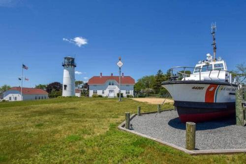 a boat on display in front of a lighthouse at Quintessential Cape directly on the Cape Cod Rail Dog Friendly in Chatham