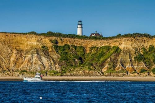 a boat on the beach with a lighthouse in the background at Beautiful backyard pool deeded beach rights in Truro