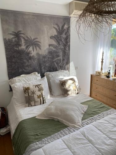 1 dormitorio con 1 cama grande con sábanas y almohadas blancas en Bel appartement en résidence avec 3 piscines, en Mandelieu-la-Napoule