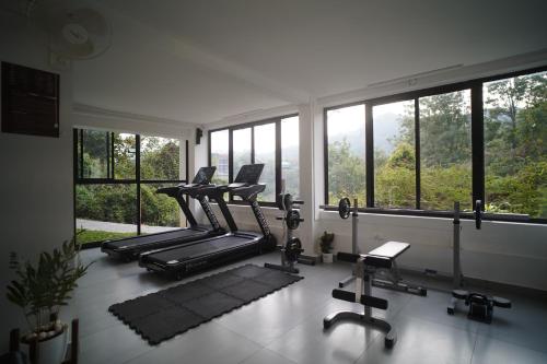 a gym with several treadmills and chairs and windows at Rivulet Resort in Munnar