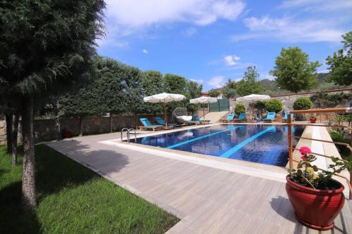 a swimming pool with chairs and umbrellas in a yard at Villa TN - Fethiye in Fethiye