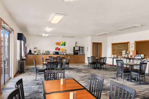 a dining room with tables and chairs and a kitchen at Quality Inn Cheyenne I-25 South in Cheyenne