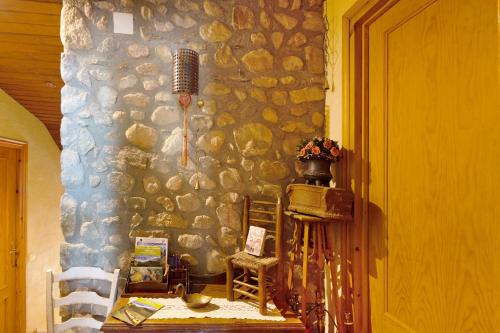 Habitación con pared de piedra, mesa y sillas. en Mas Cal Gintó, en Das