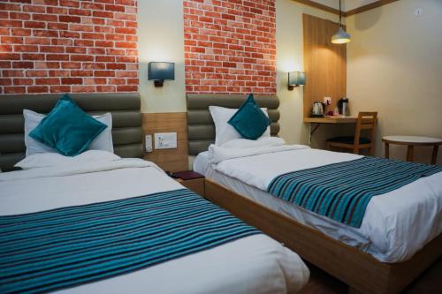 um quarto de hotel com duas camas e uma parede de tijolos em HOTEL EVERLAND em Rajkot