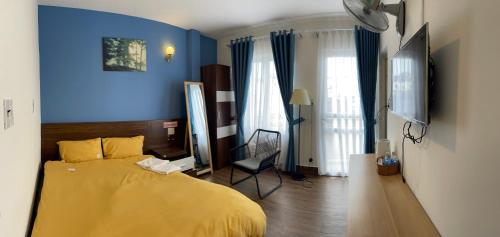 um quarto com uma cama amarela e uma parede azul em My House Hotel em Da Lat