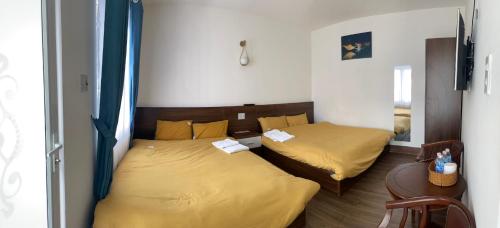 duas camas num quarto com lençóis amarelos em My House Hotel em Da Lat