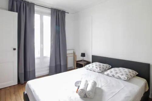 une chambre avec un lit blanc avec des oreillers et une fenêtre dans l'établissement Charmant appartement à Paris, à Paris