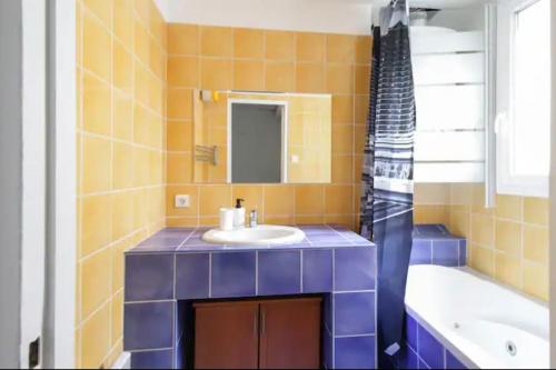 une salle de bain carrelée bleue avec un lavabo et une baignoire dans l'établissement Charmant appartement à Paris, à Paris