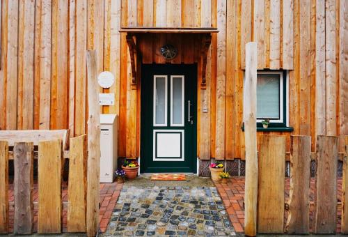 a wooden building with a black door and a window at Ferienhaus Emilia in Wilthen