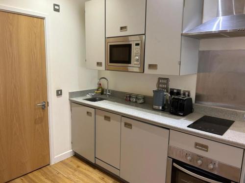 a kitchen with white cabinets and a microwave at Harford House Studios 11- Hopewell in Bristol