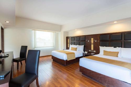 Habitación de hotel con 2 camas y escritorio en Comfort Inn Puebla Centro Historico en Puebla