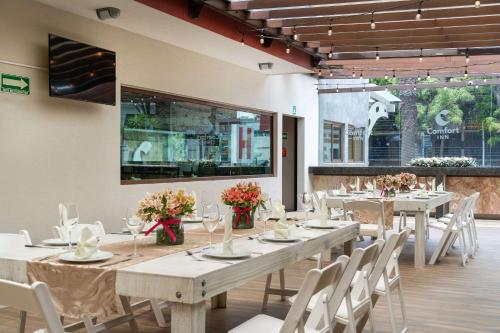 uma sala de jantar com mesas brancas e cadeiras brancas em Comfort Inn Puebla Centro Historico em Puebla