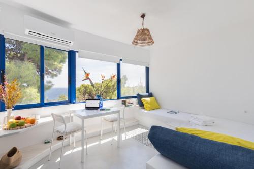 een witte kamer met een bed, een bureau en een aantal ramen bij Renovated Seaside Cabin in Sounio in Sounio