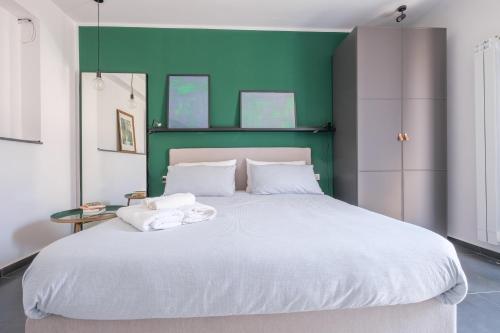 a bedroom with a large white bed with a green headboard at Ninai Sea Holiday Apartment 2 in Furci Siculo