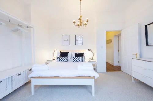 a white bedroom with a white bed and a chandelier at Kingsdown 2 bed in Bristol