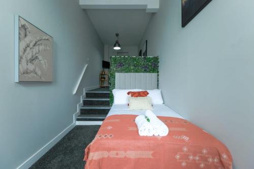 a bedroom with a bed with orange blanket and stairs at 526 Gloucester Flat 1 - Hopewell in Bristol