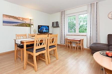 ein Wohnzimmer mit einem Tisch, Stühlen und einem Sofa in der Unterkunft Landhaus am Grafthof in Neuharlingersiel