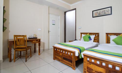 a bedroom with two beds and a table and a desk at Treebo The Anchorage Malviya Nagar in Jaipur