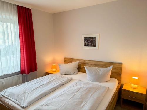 ein Schlafzimmer mit einem Bett mit einem roten Vorhang in der Unterkunft Haus Nordseeblick Wohnung 9 in Büsum