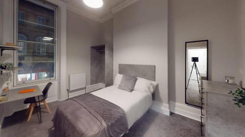 een slaapkamer met een bed, een bureau en een raam bij Queens Road five bedroom flat in Bristol