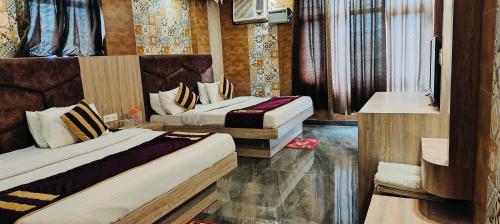 a hotel room with two beds and a television at Hotel Sunshine in Katra