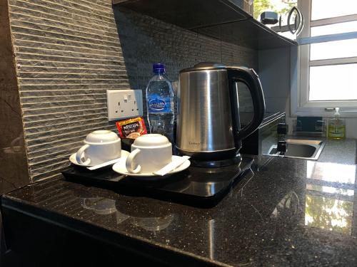 een koffiezetapparaat op een aanrecht met twee kopjes bij Newland Luxury Hotels and Apartments in Abuja