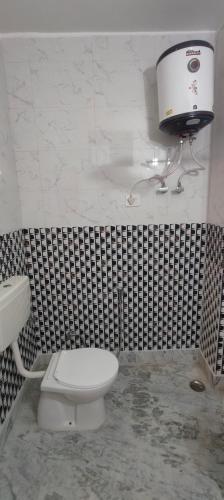 a bathroom with a white toilet and a sink at Hotel Sunshine in Katra