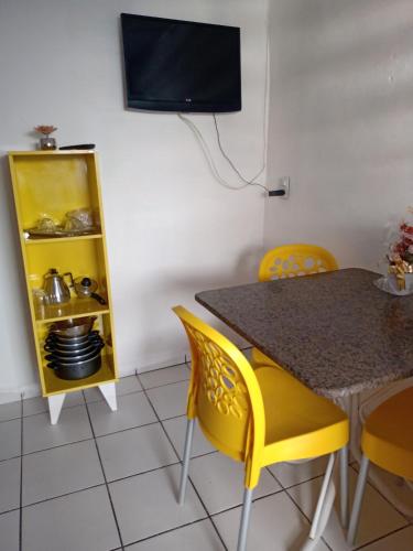 a dining room with a table and yellow chairs at Kitnet aconchegante in Olinda
