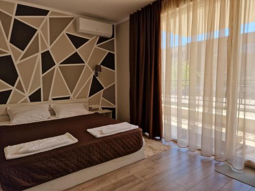 een slaapkamer met een bed en een groot raam bij Морските Апартаменти на НИКО in Nesebar