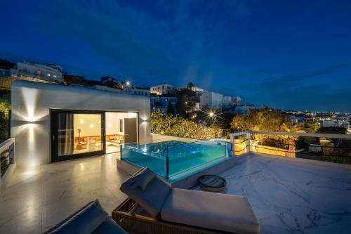 a villa with a swimming pool at night at Numi Suites in Mýkonos City