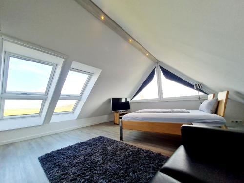 a bedroom with a bed and two large windows at Sandbank in Sankt Peter-Ording
