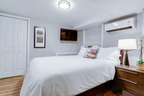 a white bedroom with a large bed and a lamp at Beautiful 2 Bedroom across from The House of Representatives in Washington, D.C.